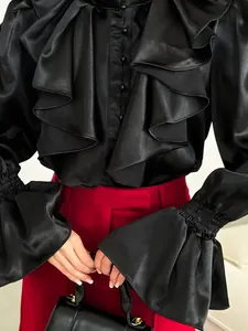 Close-up detail of an elegant black satin blouse featuring ruffled collar and flared sleeves