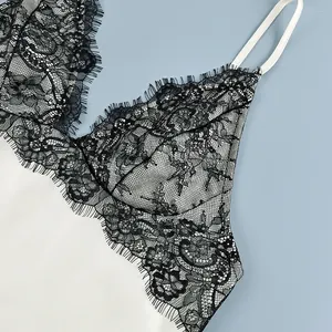 Detailed macro shot of elegant black eyelash lace trim on white satin camisole top