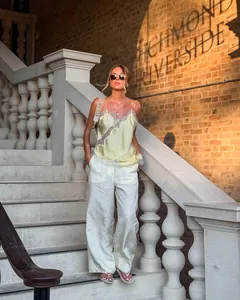 Model im asymmetrischen Spitzen-Top und weißer weit geschnittener Hose auf Treppe