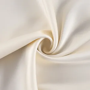 Macro view of luxurious cream satin fabric showing its smooth texture and elegant luster