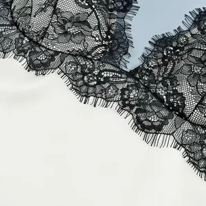Detailed view of exquisite black floral lace texture and eyelash trim on a modern camisole
