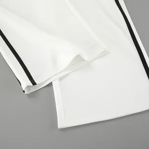 Vue détaillée du bas de pantalon blanc avec bande latérale noire.