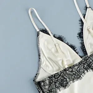 Macro detail view of a white satin camisole featuring black eyelash lace trim and straps.