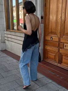 Schickes schwarzes asymmetrisches Camisole mit Spitzenbesatz und tiefem Rücken.