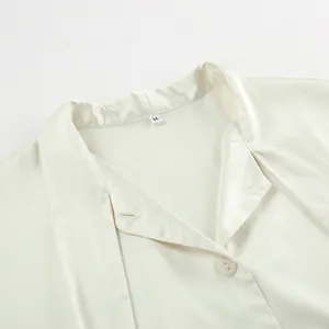 Close-up detail of a silky ivory satin blouse with an elegant tie-neck collar