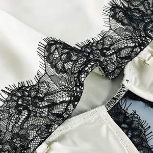Exquisite close-up detail of black eyelash lace trim on a cream white satin camisole top