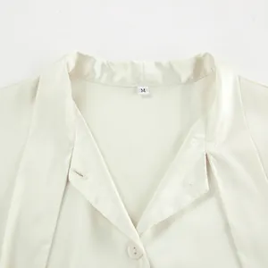 Close-up detail of cream satin tie-neck blouse with elegant silk texture