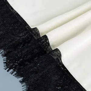 Close-up detail of white satin fabric with delicate black eyelash lace trim for women