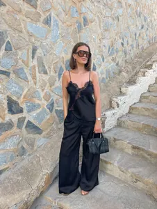 Detailansicht der asymmetrischen Spitzenverzierung an einem schwarzen Satin-Camisole-Top