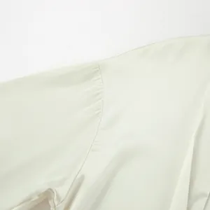 Close-up detail of the shoulder seam on a cream satin blouse with smooth fabric texture