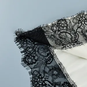 Detailed macro view of delicate black eyelash lace trim on a cream satin camisole top