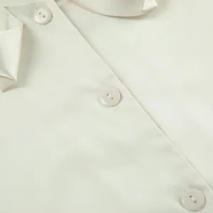 Detailed close-up showing the smooth texture and elegant buttons of a cream satin blouse
