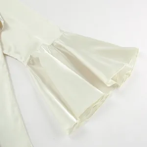 Detailed macro shot showing the luxury satin fabric and flare ruffle sleeves of the ivory blouse