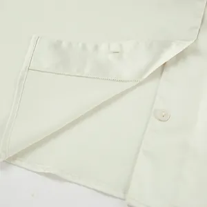 Close-up of premium satin fabric texture and delicate hemline stitching on white shirt