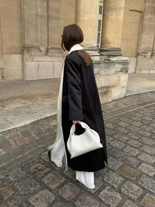 Elegant white satin belt with long fringes styled with a black coat in a street setting