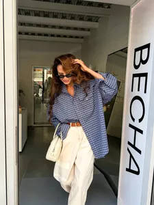 Detail view of a vintage blue plaid cotton shirt on a model in a stylish boutique setting.