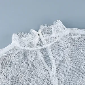 Détail en gros plan montrant les motifs complexes de dentelle florale blanche et le col