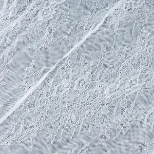 Gros plan détaillé montrant un tissu en dentelle florale blanche avec un motif de maille fin.