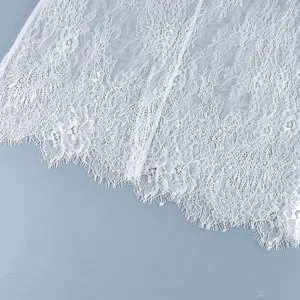 Détail en gros plan d'un tissu en dentelle florale blanche avec une bordure en cils.