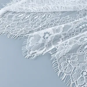 Gros plan sur un tissu en dentelle florale blanche avec bords en franges