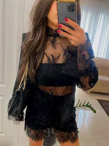 Détail d'une robe en dentelle noire transparente à manches longues et motifs floraux