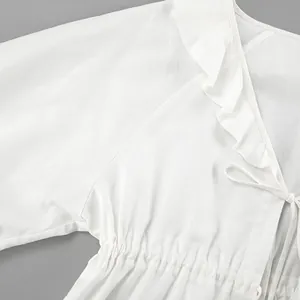 Macro detail of white cotton linen top featuring elegant ruffle trim and waist tie