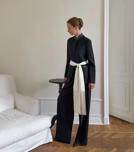 Elegant white satin fringed belt cinching a black blazer for a high-end fashion look.