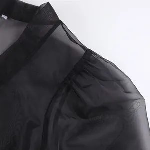 Dettaglio ravvicinato della spalla di una camicia nera in rete trasparente fine