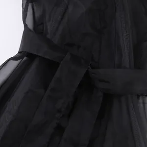Primo piano della cintura in vita e della trama del tessuto della camicia in rete nera velata.