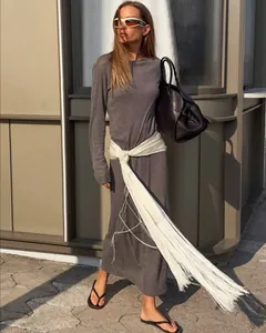 Fashionable white satin waist belt with long fringe detail worn on a grey dress