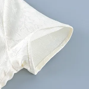 Close-up of white textured short sleeve shirt showing elegant jacquard leaf pattern.