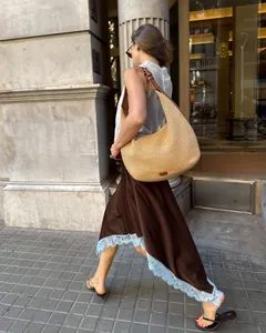 Woman walking in a brown satin midi skirt with light blue lace trim detailing at the hem.