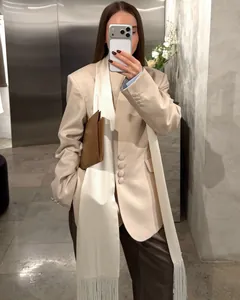Close-up of white satin sash with elegant fringe trim on a beige blazer outfit.