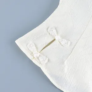 Detail shot of traditional Chinese knot buttons on a textured white shirt blouse