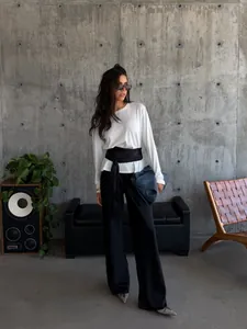 Elegant black satin wrap belt with tassels styled on a model in a minimalist setting.