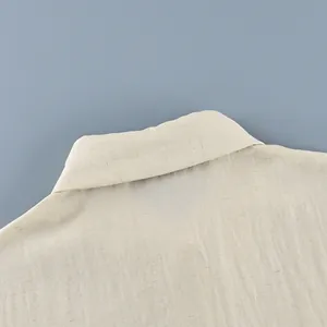Detailed macro view of the beige linen fabric texture and collar of a French style wrap shirt