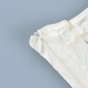 Close-up of white invisible zipper and knot button on cream jacquard shirt detail