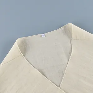 Detail view of the elegant V-neckline and linen fabric texture of this cream wrap shirt