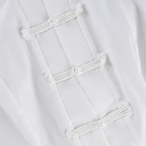 Primer plano de los tradicionales botones chinos blancos en una blusa de estilo Neochino