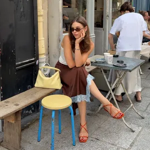 Detail of a brown satin midi skirt with blue lace trim in a street style setting