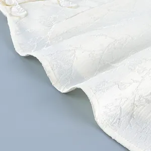 Close-up of white jacquard fabric and traditional Chinese knot buttons on a vintage shirt.