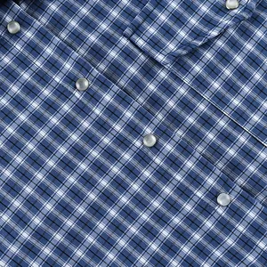 Close-up of blue plaid cotton shirt showing pearl snap buttons and fabric texture.
