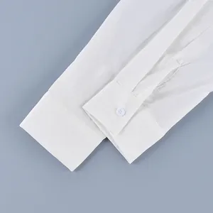 Primer plano detallado del puño de una camisa blanca con costuras limpias y un botón blanco.