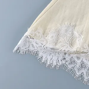 Close-up of delicate white eyelash lace trim on a beige French style linen blouse