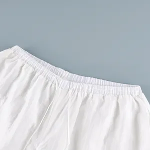 Close-up detail of white semi-sheer trousers featuring elastic waistband and drawstring