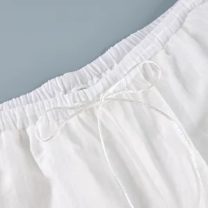 Close-up of elastic waistband with decorative white drawstring bow on sheer pants.