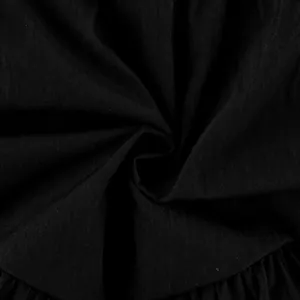 Macro view showing the breathable black fabric texture and ruffled details of the midi skirt