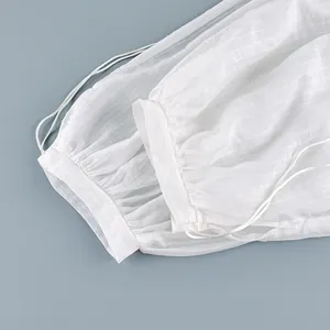 Detail of white semi-transparent trousers showing drawstring cuffs and striped texture.