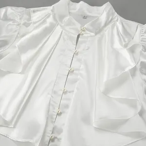 Detailed view of white satin ruffle shirt with elegant pearl buttons and stand collar