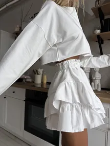 Detailed side view of white high-waisted tiered ruffle cake skirt and matching cropped top